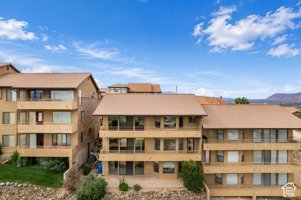 Multi-level exterior featuring tan stucco siding, expansive concrete balconies, tiled roof, and expansive windows