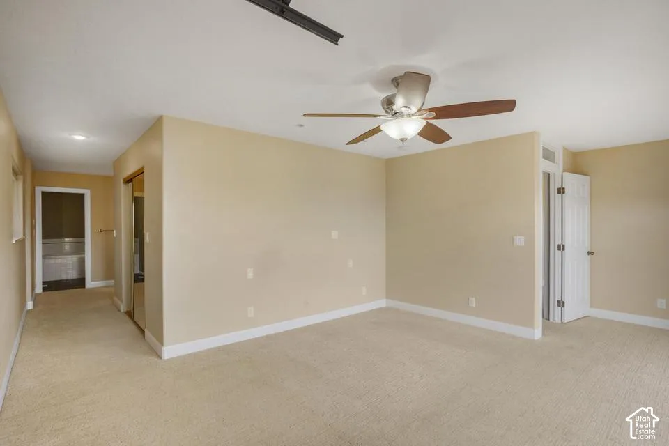 Neutral-toned interior featuring wall-to-wall carpeting, a ceiling fan with integrated light fixture, recessed lighting, and white paneled doors