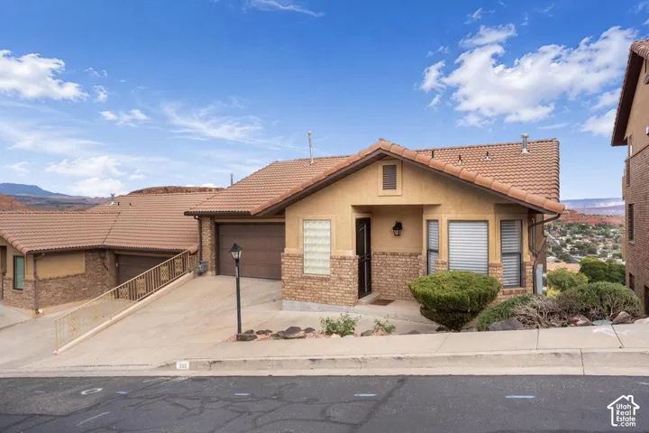 Stucco and brick facade with a tiled roof, multi-car garage, and concrete driveway