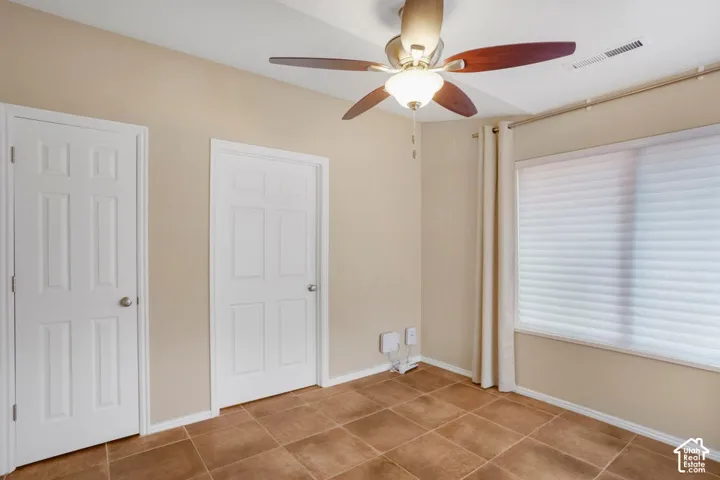 Tile flooring, neutral wall tones, multi-panel doors, and a ceiling fan with integrated lighting