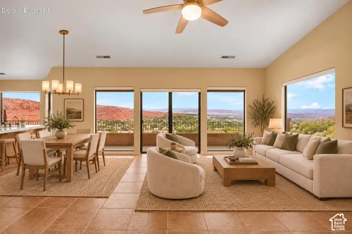 Open-concept space featuring vaulted ceilings, tile flooring, a multi-light chandelier, a ceiling fan with integrated lighting, and expansive windows showcasing rock formation scenery