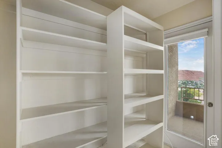 White built-in shelving featuring fixed storage tiers and a glass-paneled door leading to an exterior balcony with mesa landscape surroundings