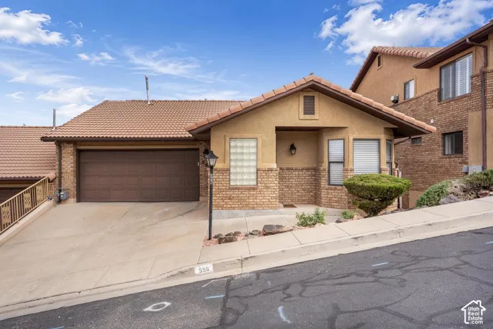 Stucco and brick facade with a tiled roof, attached two-car garage, and glass block accent window
