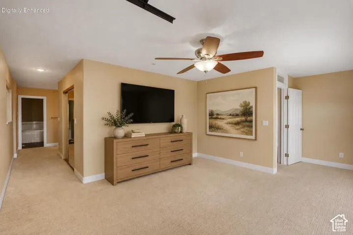 Spacious room featuring neutral wall tones, wall-to-wall carpeting, and a ceiling fan with integrated lighting