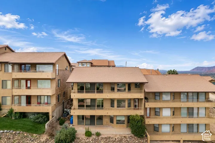 Multi-level exterior featuring tan stucco siding, expansive concrete balconies, tiled roof, and expansive windows