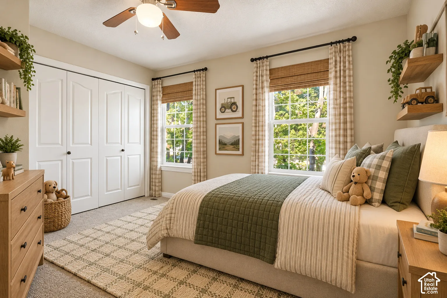 Neutral-toned bedroom featuring dual windows with woven wood shades, wall-mounted floating wood shelving, a ceiling fan with light fixture, and a spacious double-door closet with paneled detailing