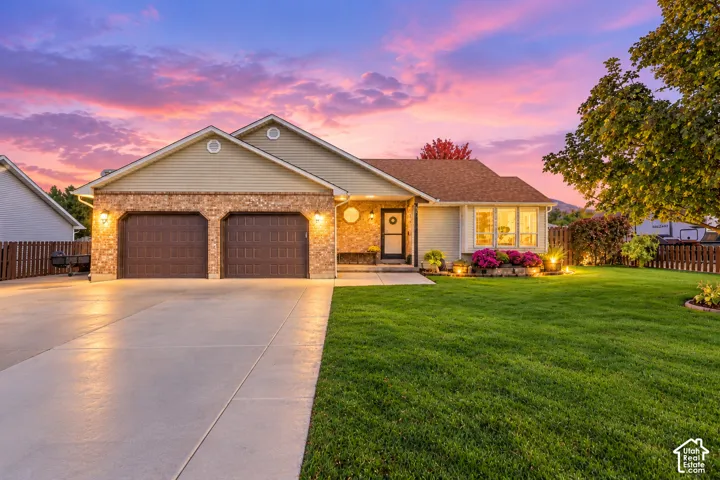 Ranch-style exterior featuring horizontal lap siding, brick masonry, a concrete driveway, a two-car garage, and a manicured front lawn