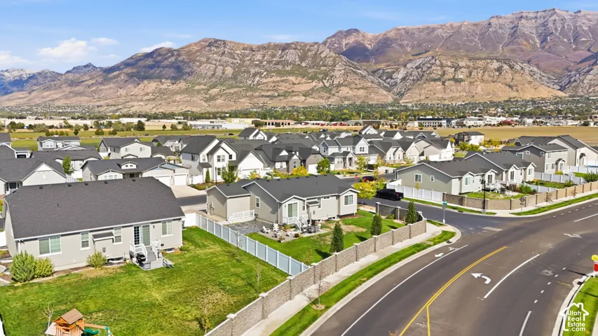 Aerial perspective of the residential area featuring a mountain backdrop, perimeter masonry fencing, and manicured lawns