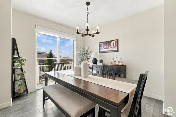 Dining area featuring wood-finish flooring, a multi-arm chandelier with clear glass shades, and a large sliding glass door with a grid pattern