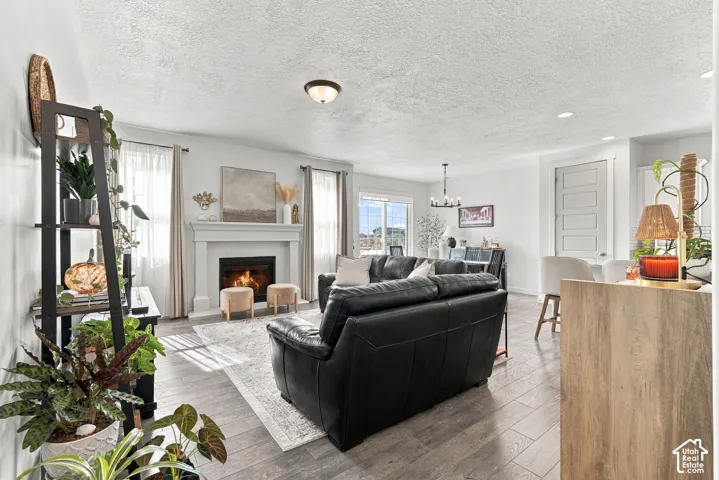 Living area featuring wood-finish flooring, a fireplace with a custom mantle, recessed lighting, and a multi-panel door