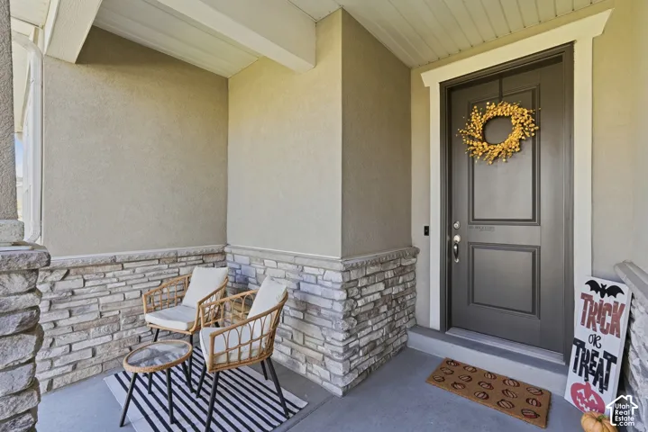 Covered front entryway featuring stone veneer siding, concrete porch flooring, and a paneled entry door