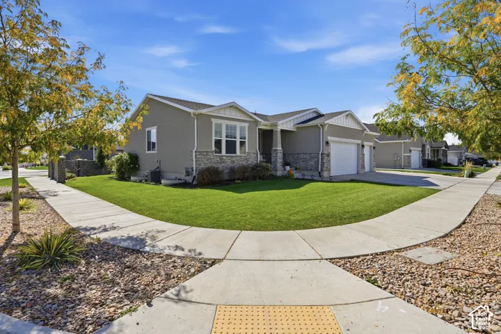 Single-story residence featuring a stone veneer facade, horizontal siding, attached multi-car garage, concrete driveway, and manicured lawn