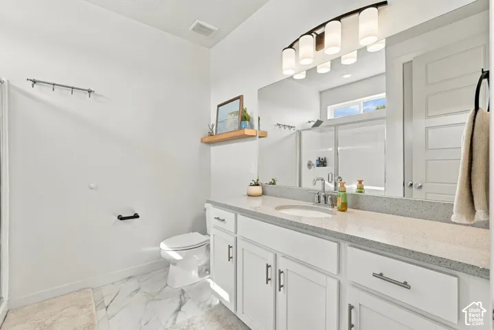 Bathroom featuring a vanity with white cabinetry, a stone-composite countertop, an integrated sink, marble-finish tile flooring, and a five-light vanity fixture