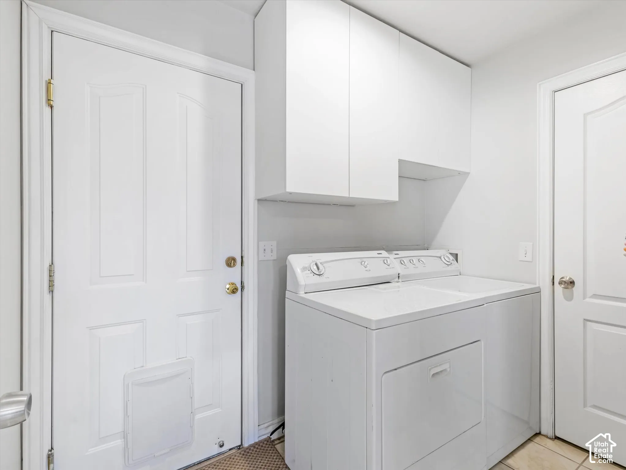 Laundry area featuring white cabinetry, a paneled door with integrated pet door, and tile flooring