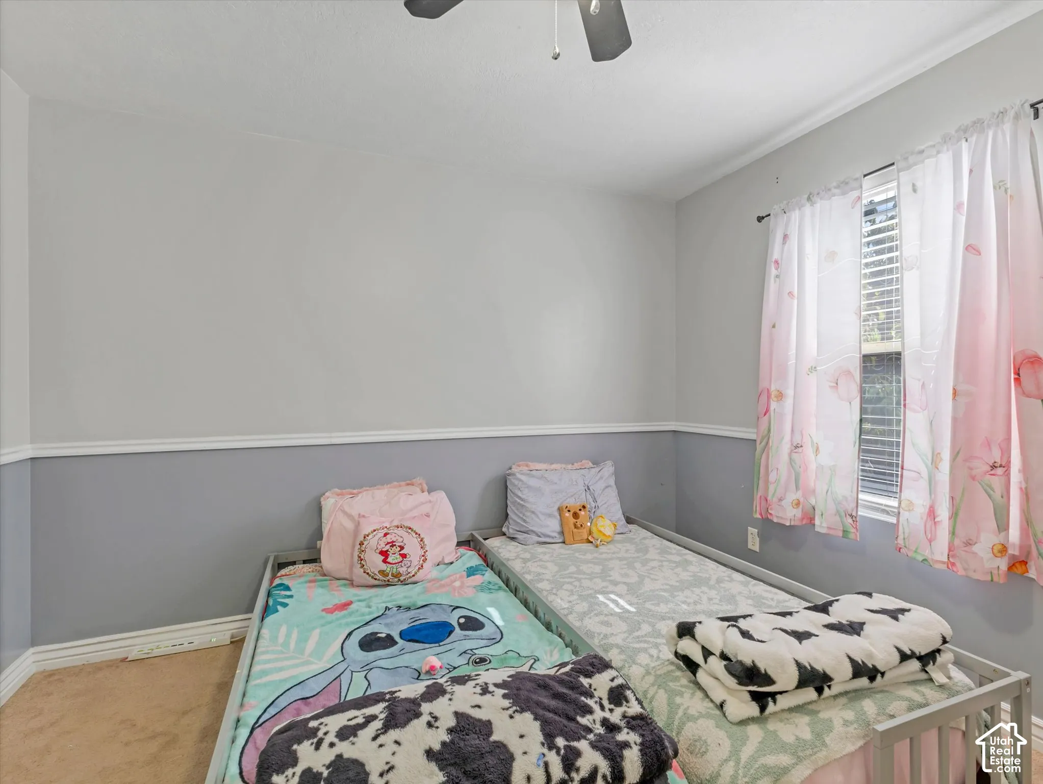 Neutral interior walls with decorative chair rail molding, ceiling-mounted light fixture with fan, and window featuring horizontal blinds