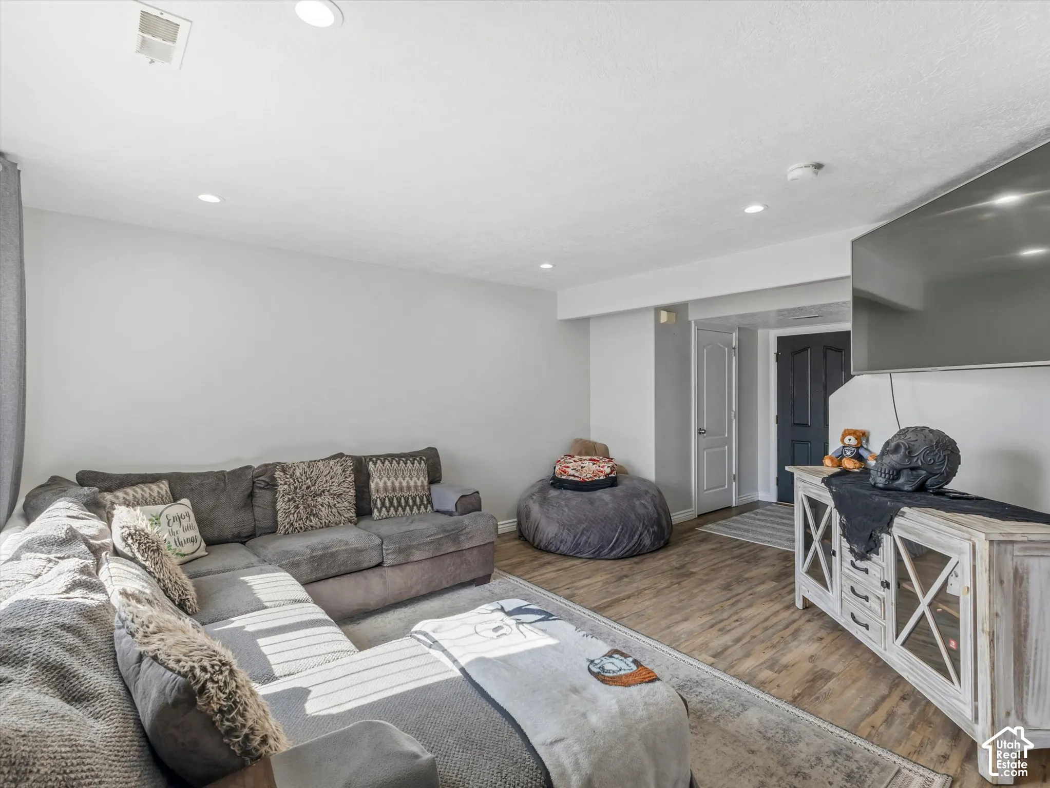 Neutral interior space featuring wood-finish flooring, recessed lighting, and a multi-panel door