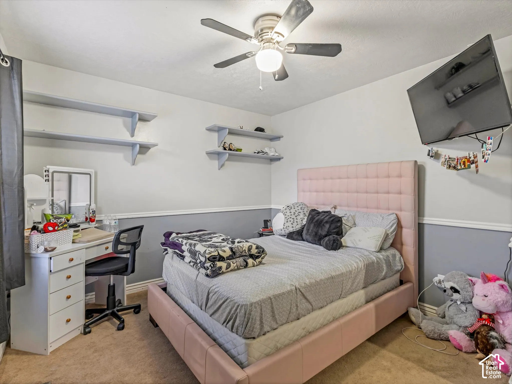 Bedroom featuring dual wall-mounted floating shelves, chair rail molding, and a central ceiling fan with integrated lighting