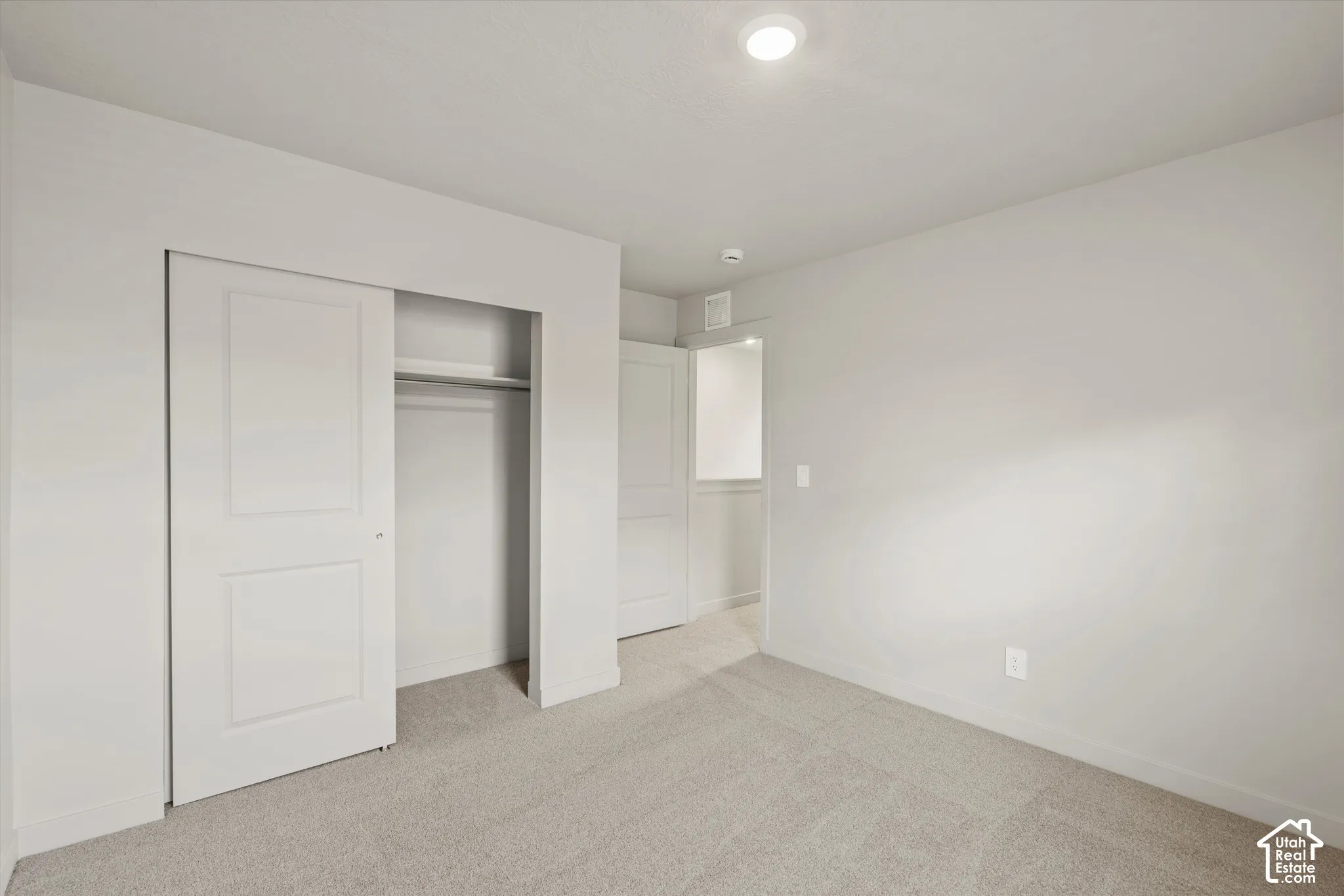 Neutral-toned wall paint, recessed lighting, wall-to-wall carpeting, and sliding panel closet doors
