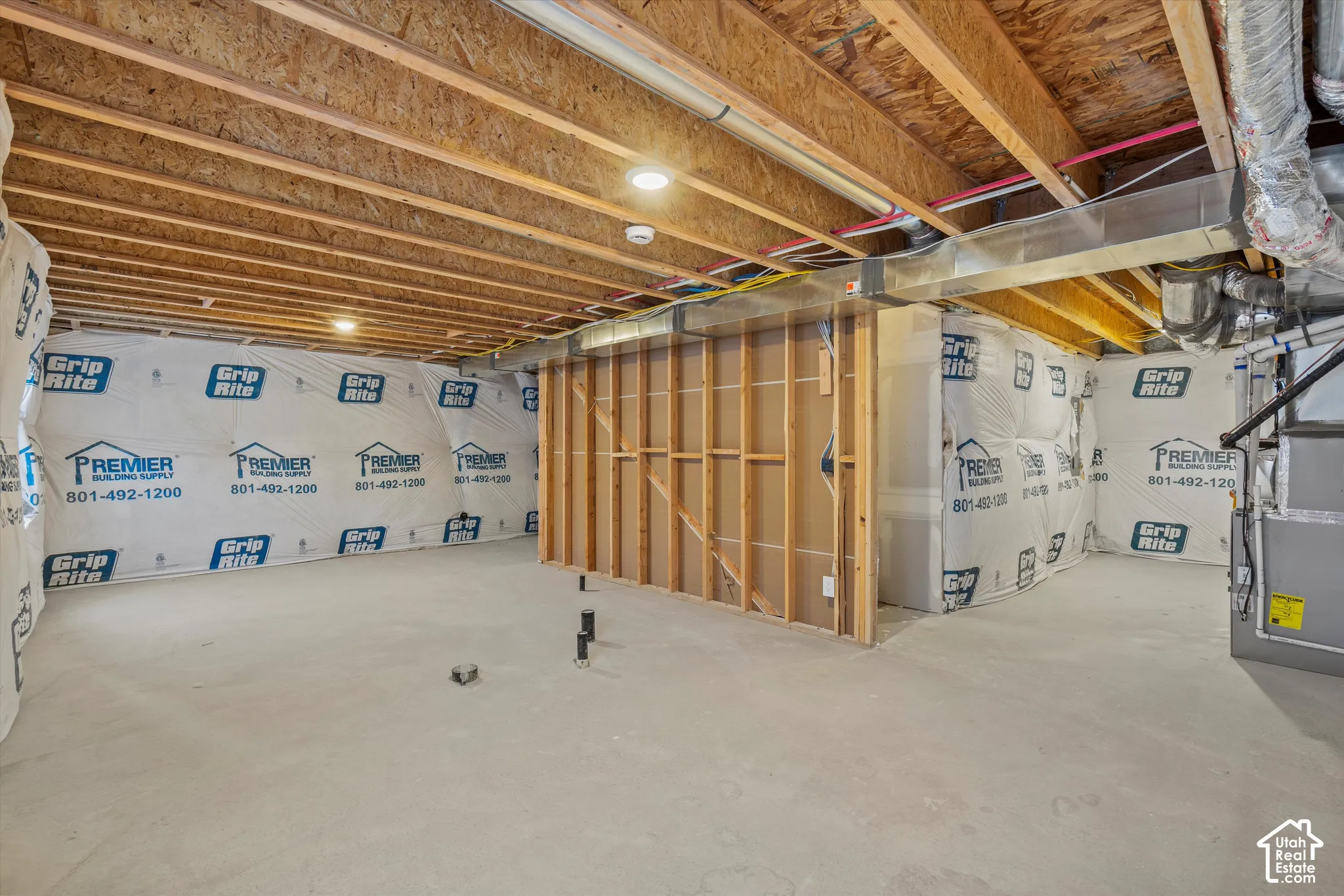 Unfinished lower level featuring exposed wood joist ceilings, concrete flooring, vapor barrier foundation wall wraps, and mechanical system access
