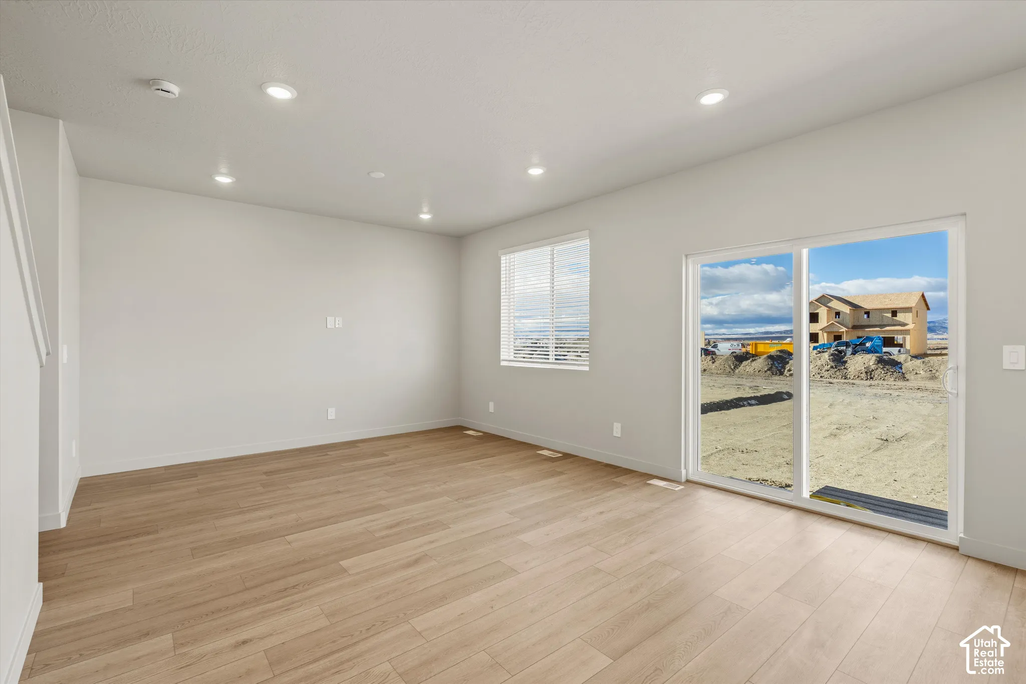 Open floor plan featuring neutral paint, wood-finish flooring, recessed lighting, and large sliding glass doors