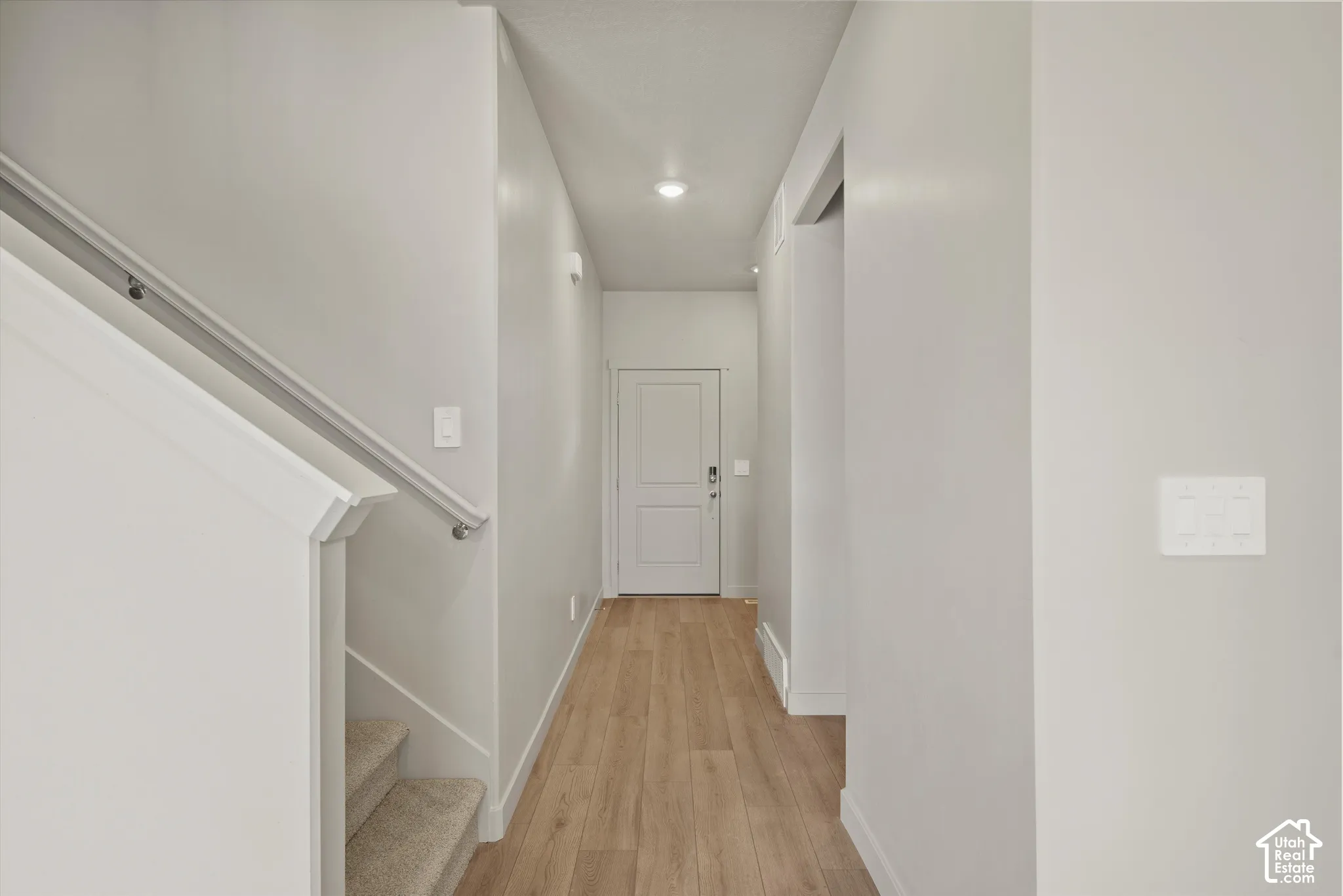 Entryway featuring wood-finish flooring, a neutral color palette, recessed lighting, and a staircase with a white handrail