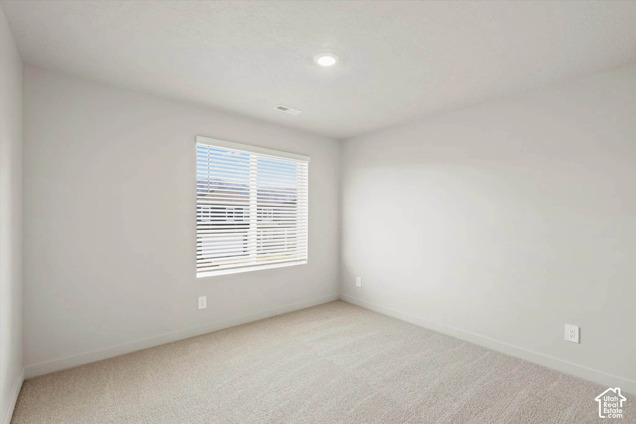 Neutral interior space featuring high-pile wall-to-wall carpeting, single-pane window with horizontal blinds, and recessed ceiling lighting