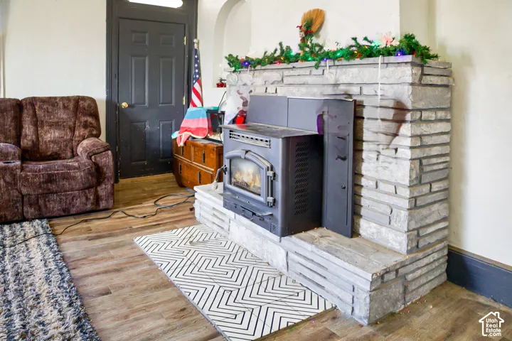 Floor-to-ceiling dry-stack stone fireplace featuring a metal insert, raised stone hearth, wood-finish flooring, and a paneled interior door