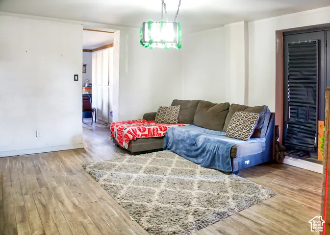 Wood-finish flooring throughout, recessed ceiling lighting, and a dark-toned door with a glass pane
