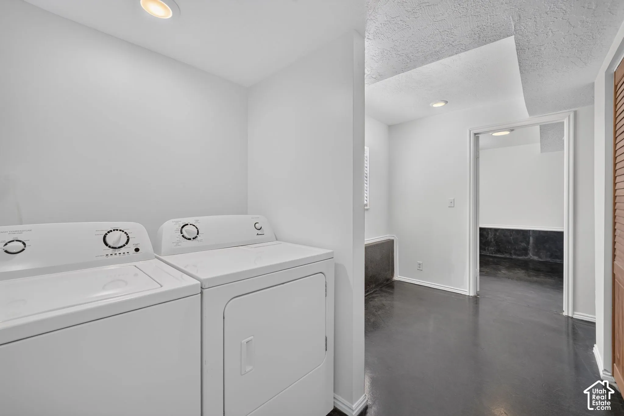 Utility area featuring high-gloss charcoal flooring, recessed lighting, and a textured ceiling finish