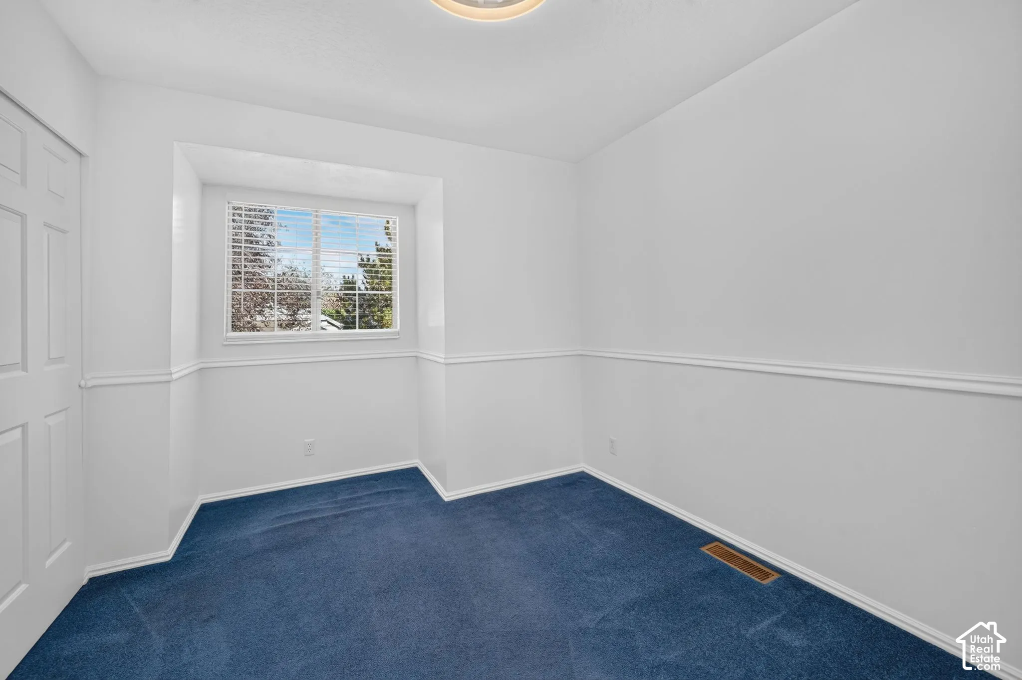 Interior space featuring blue carpeting, chair rail molding, a recessed window with interior shutters, and a ceiling-mounted light fixture