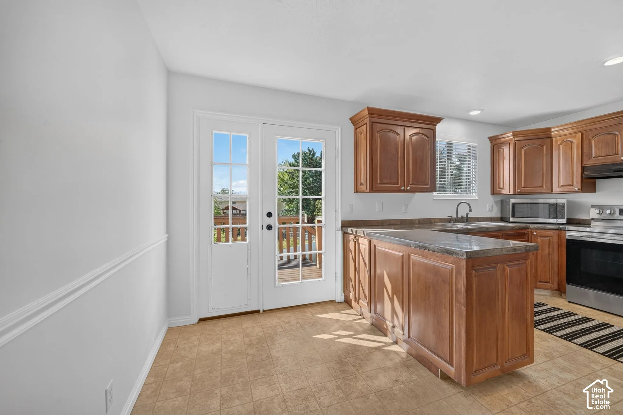 Kitchen featuring wood cabinetry, stone-finish countertops, stainless steel appliances, and a glass-paneled door with exterior access