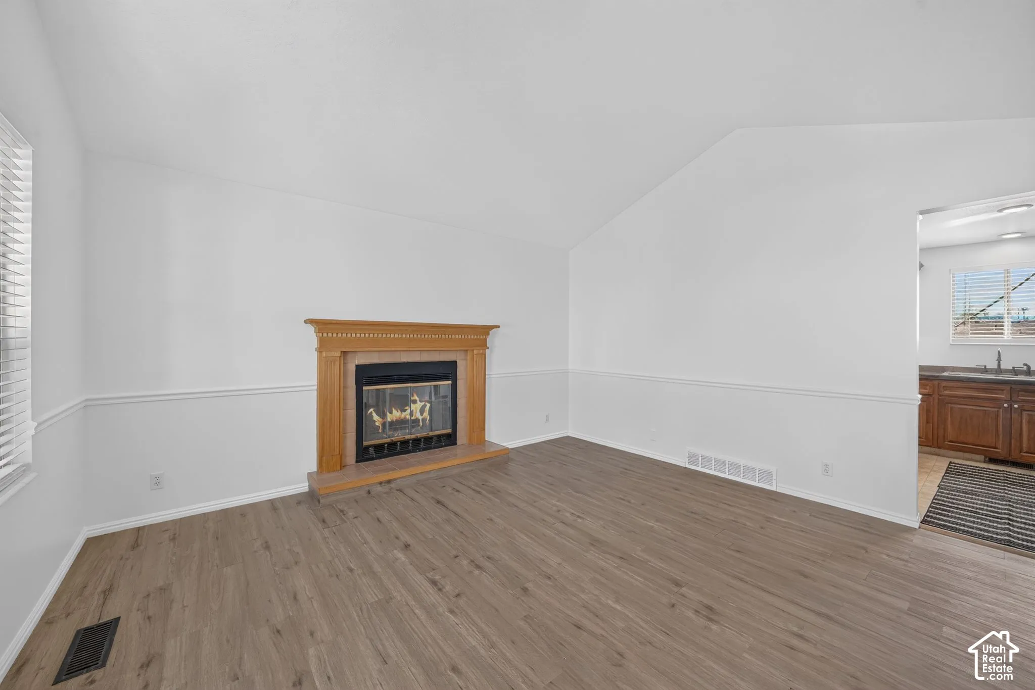Vaulted ceilings, wood-finish flooring, and fireplace with a natural wood mantel