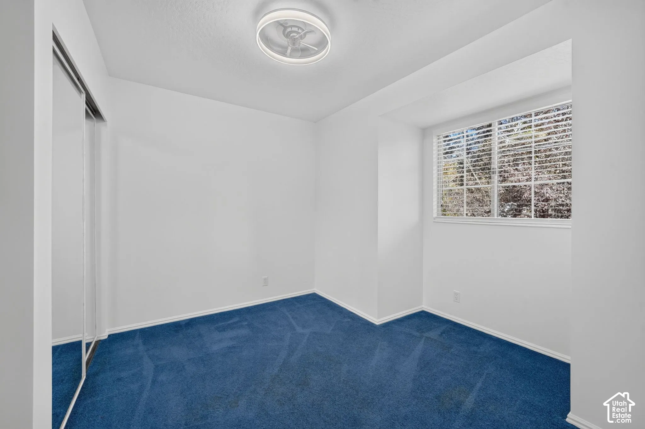 Room featuring wall-to-wall carpeting, mirrored sliding closet doors, a recessed window nook, and a circular LED flush-mount light fixture