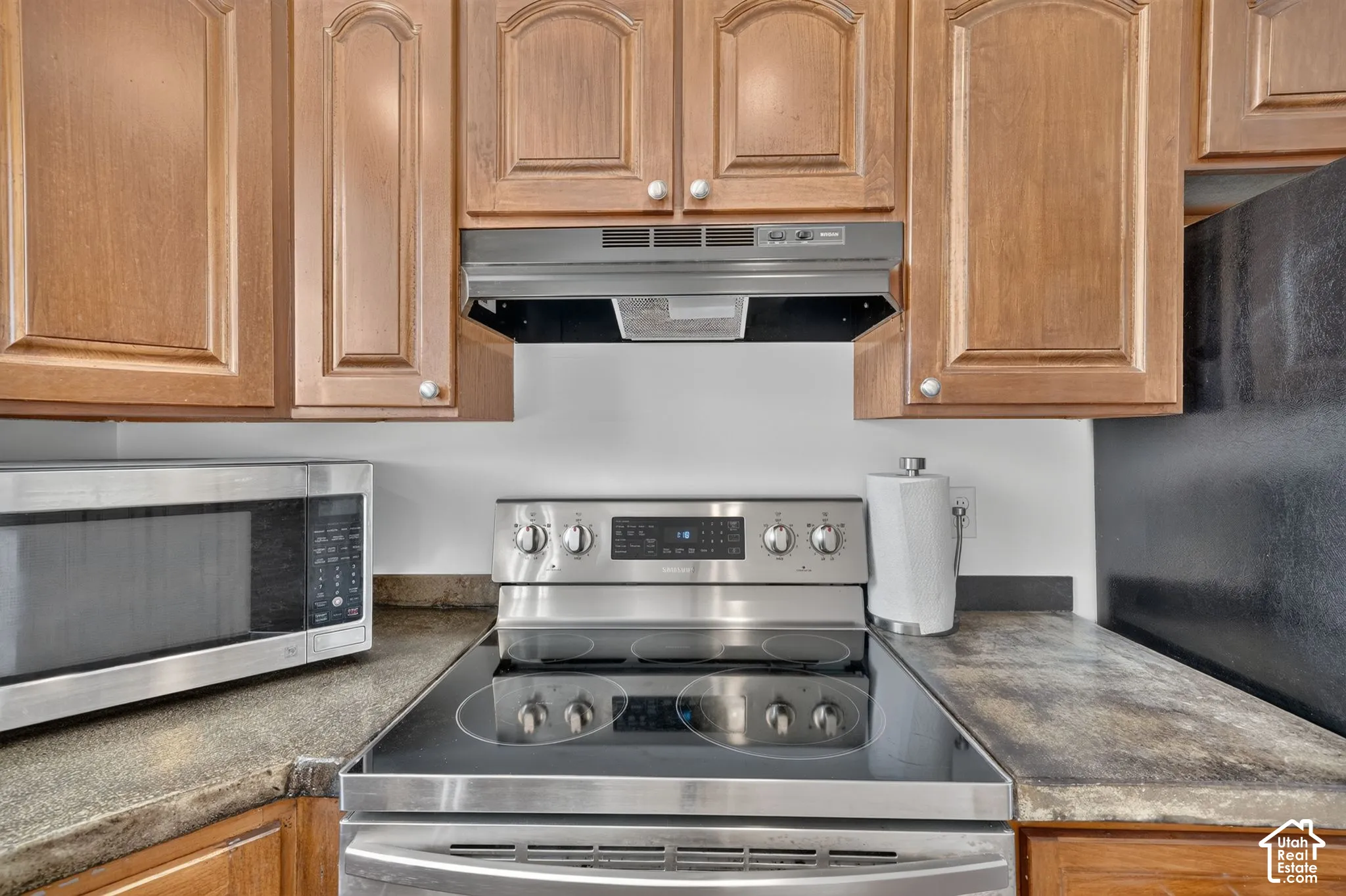 Kitchen featuring wood cabinetry, stainless steel electric range, built-in stainless steel microwave, and laminate countertops