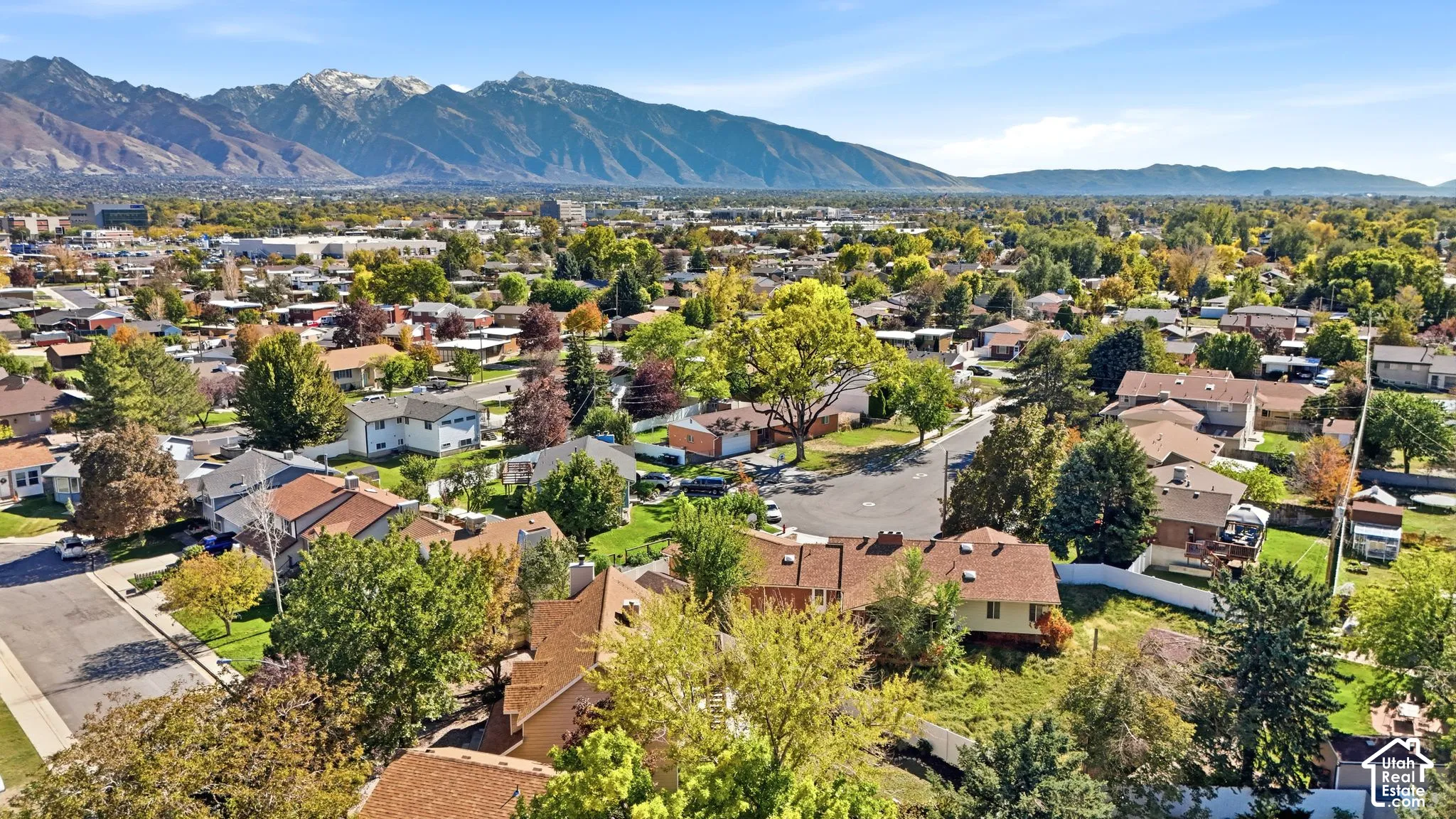 Aerial perspective featuring a prominent mountain backdrop, established residential setting, and mature landscaping