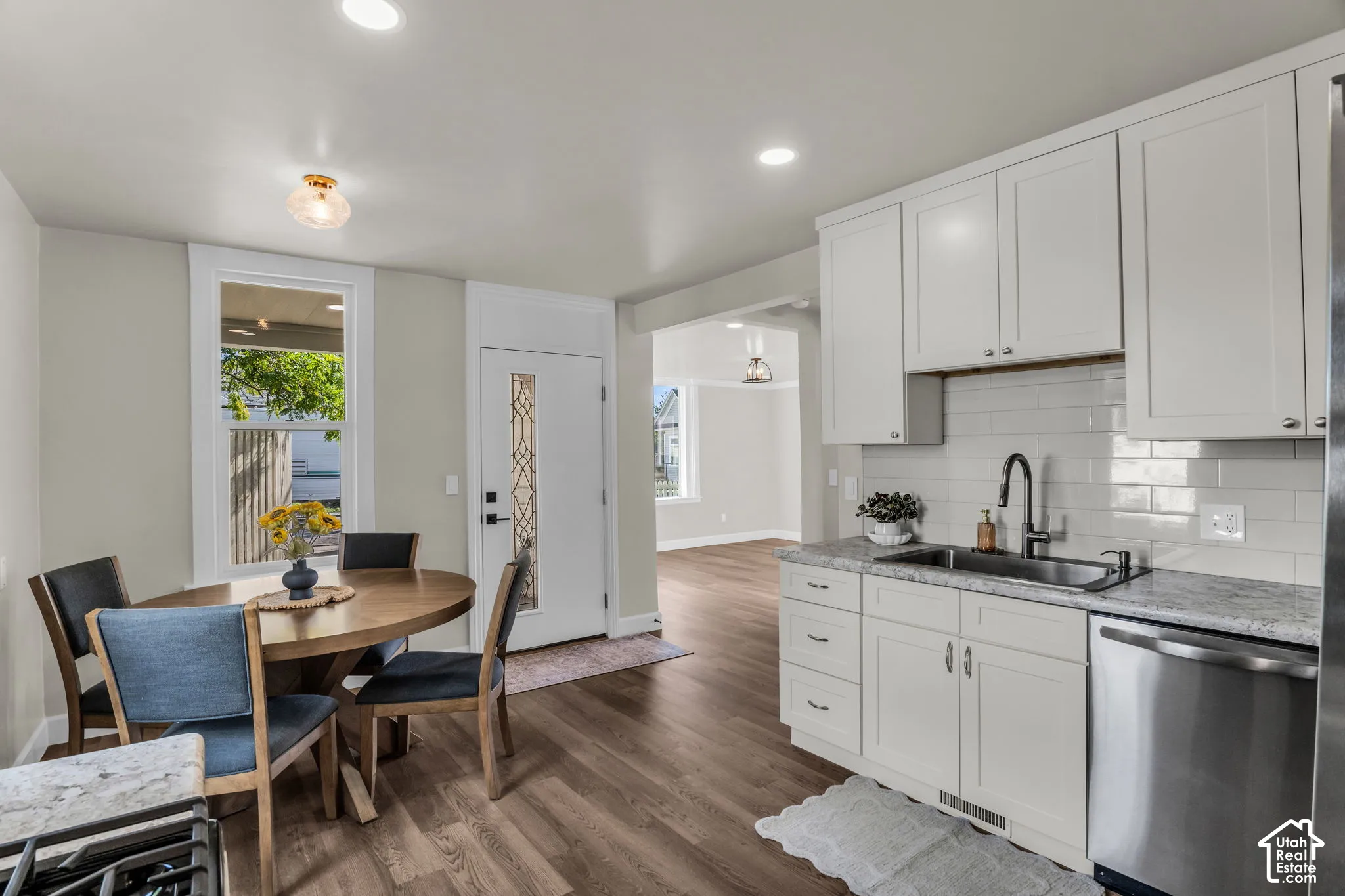 Kitchen featuring white shaker cabinetry, stainless steel appliances, light-colored countertops, and a subway tile backsplash