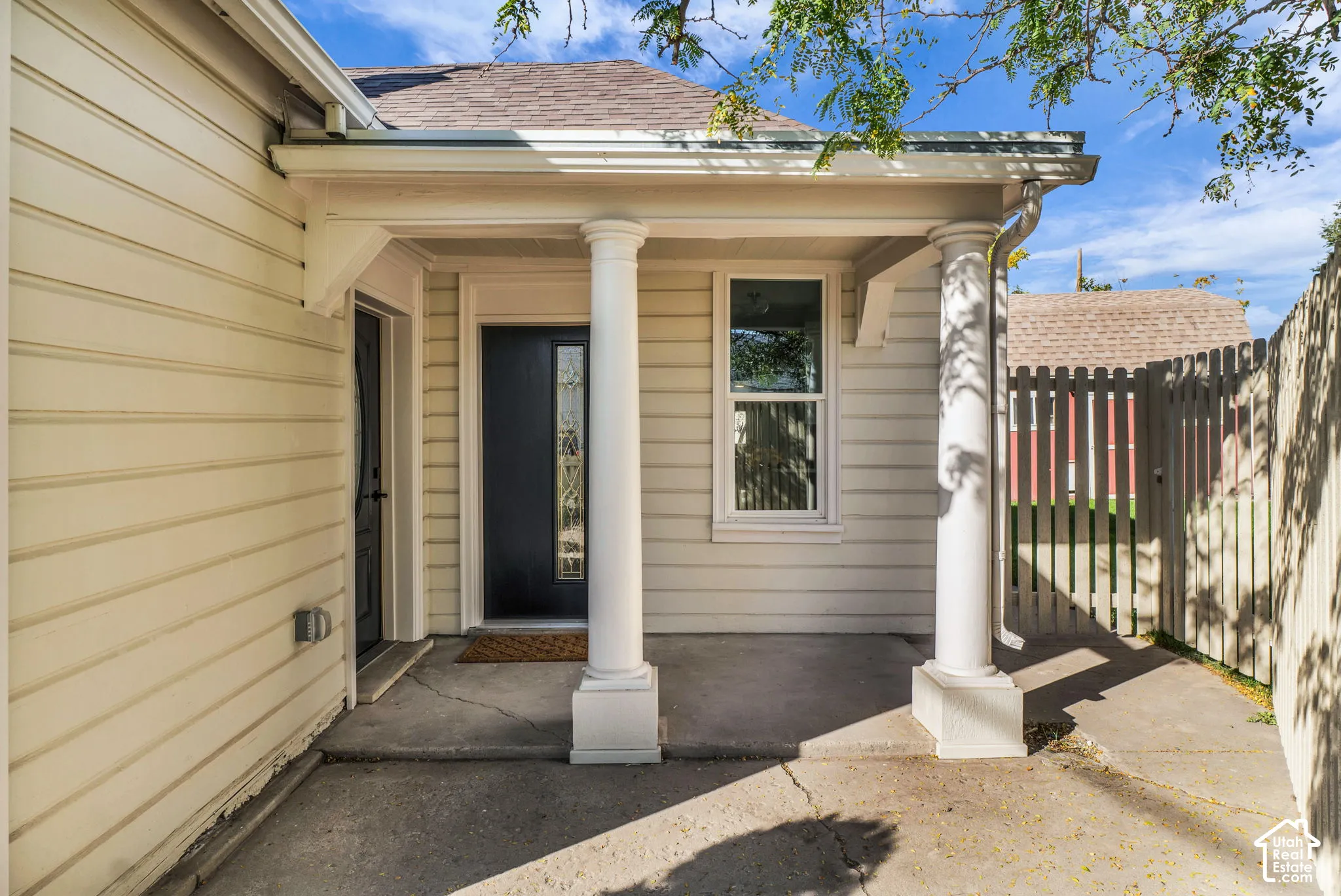 Covered front entry featuring a column, a dark paneled door with decorative glass, and horizontal siding