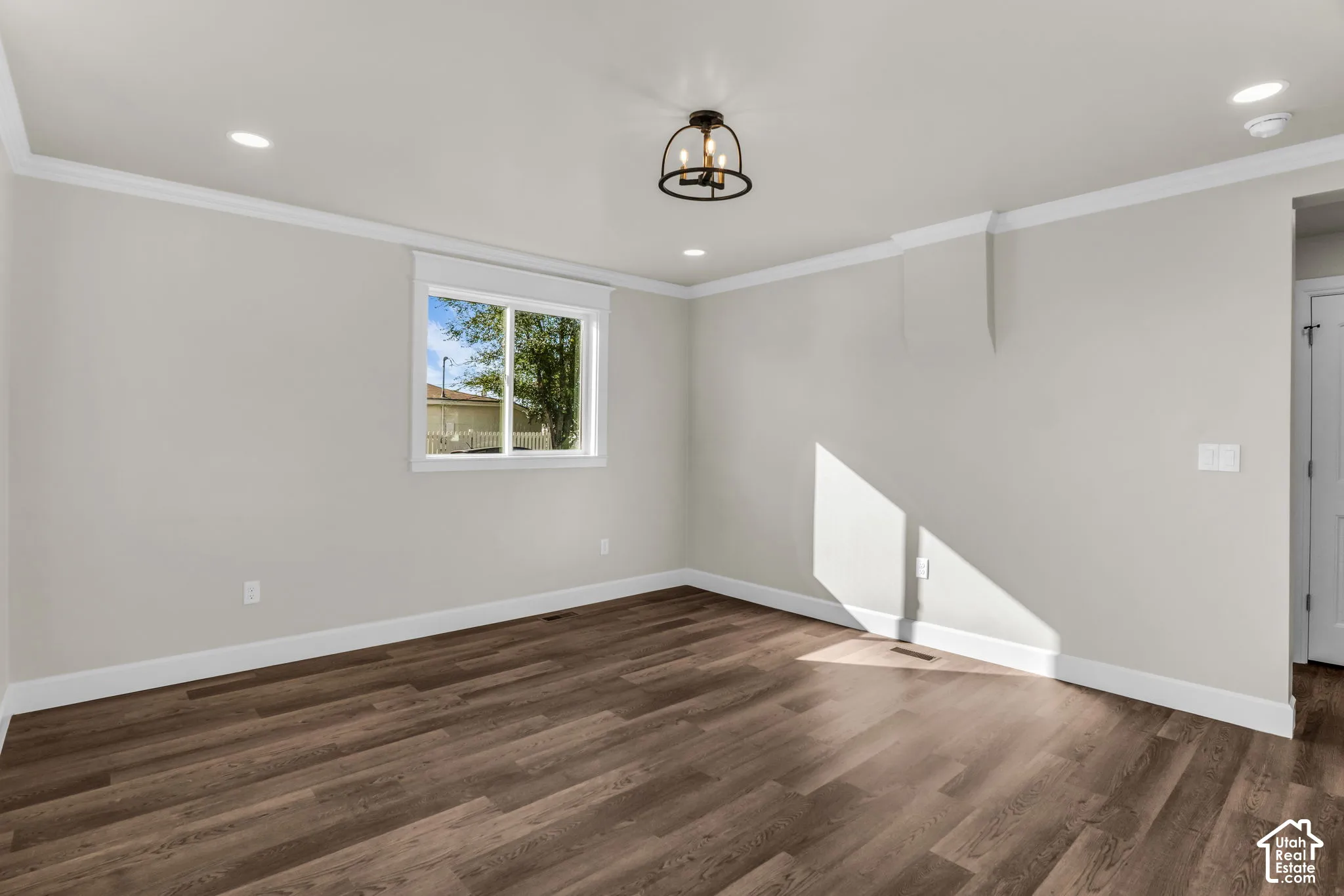 Wood-finish flooring, recessed lighting, crown molding, a modern semi-flush mount fixture, and a window with white trim