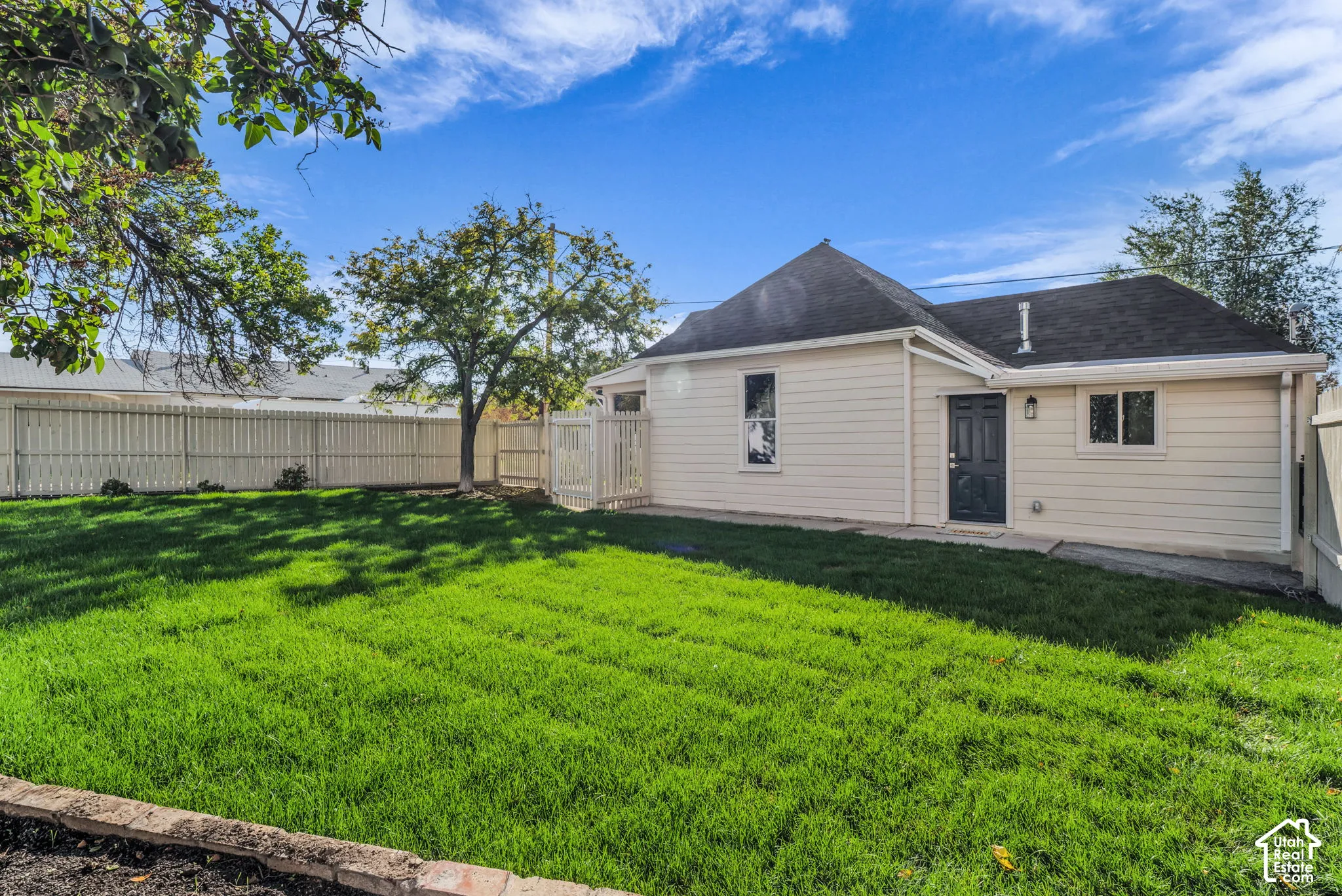 Fenced yard with a manicured lawn, featuring a light-colored exterior and a dark entry door