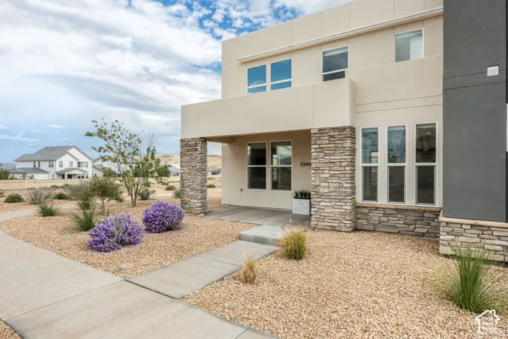 Contemporary exterior featuring multi-tonal stucco siding, stone veneer accents, multi-pane windows, and a covered entryway