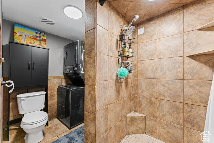 Tiled shower enclosure featuring a corner bench seat and adjustable showerhead, accompanied by a white porcelain toilet and recessed ceiling lighting