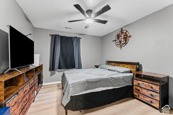 Light-toned wood-finish flooring and a central ceiling fan with integrated lighting