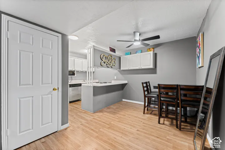Kitchen featuring a peninsula counter, white cabinetry, integrated ceiling fan with light, and wood-finish flooring