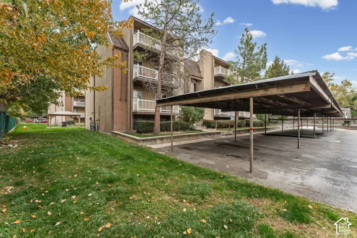 Multi-story exterior featuring brick masonry, tiered private balconies with white railings, and covered carport parking