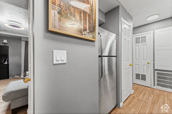 Stainless steel refrigerator, wood-finish flooring, and white multi-panel interior doors