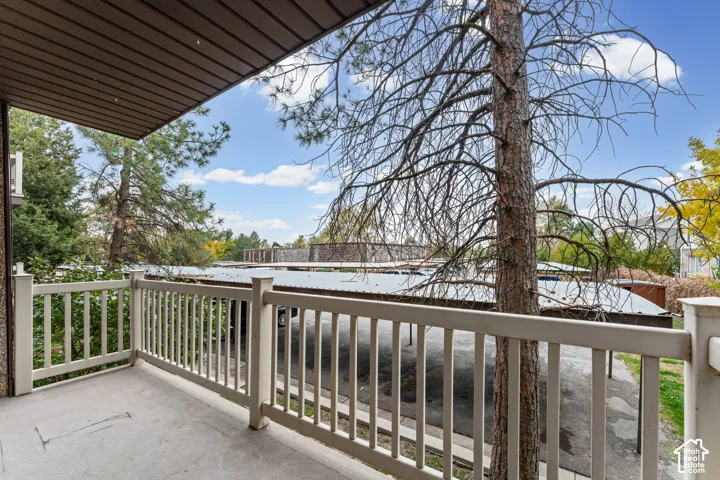 Covered balcony featuring concrete flooring and a white vertical balustrade railing