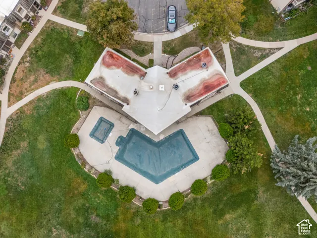 Aerial perspective featuring a concrete pool deck, in-ground swimming pool, integrated spa, and mature landscaping