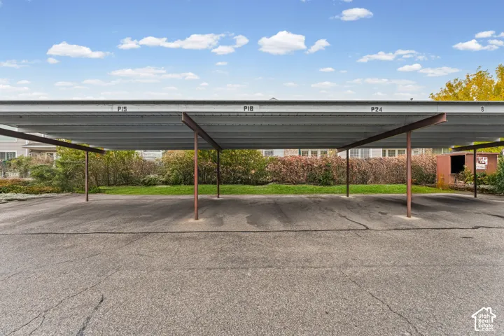 Covered parking structure featuring a metal roof, steel support beams, and asphalt paving
