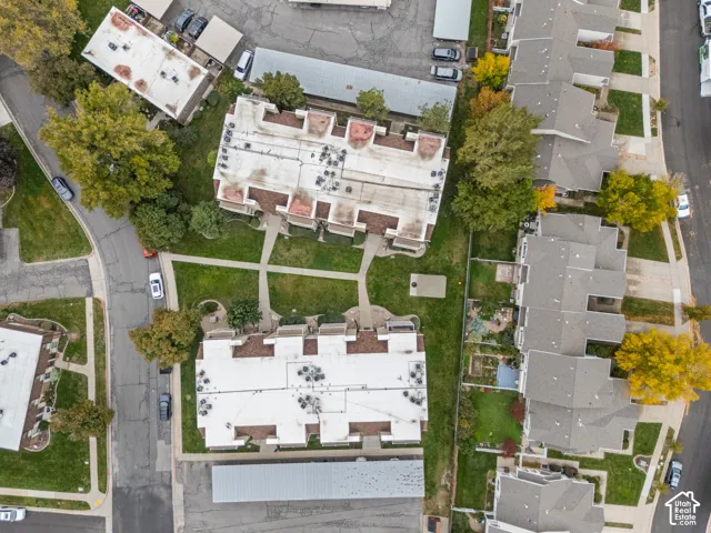 Aerial perspective of multi-family structures featuring asphalt shingle roofing, concrete walkways, dedicated covered parking areas, and mature landscaping