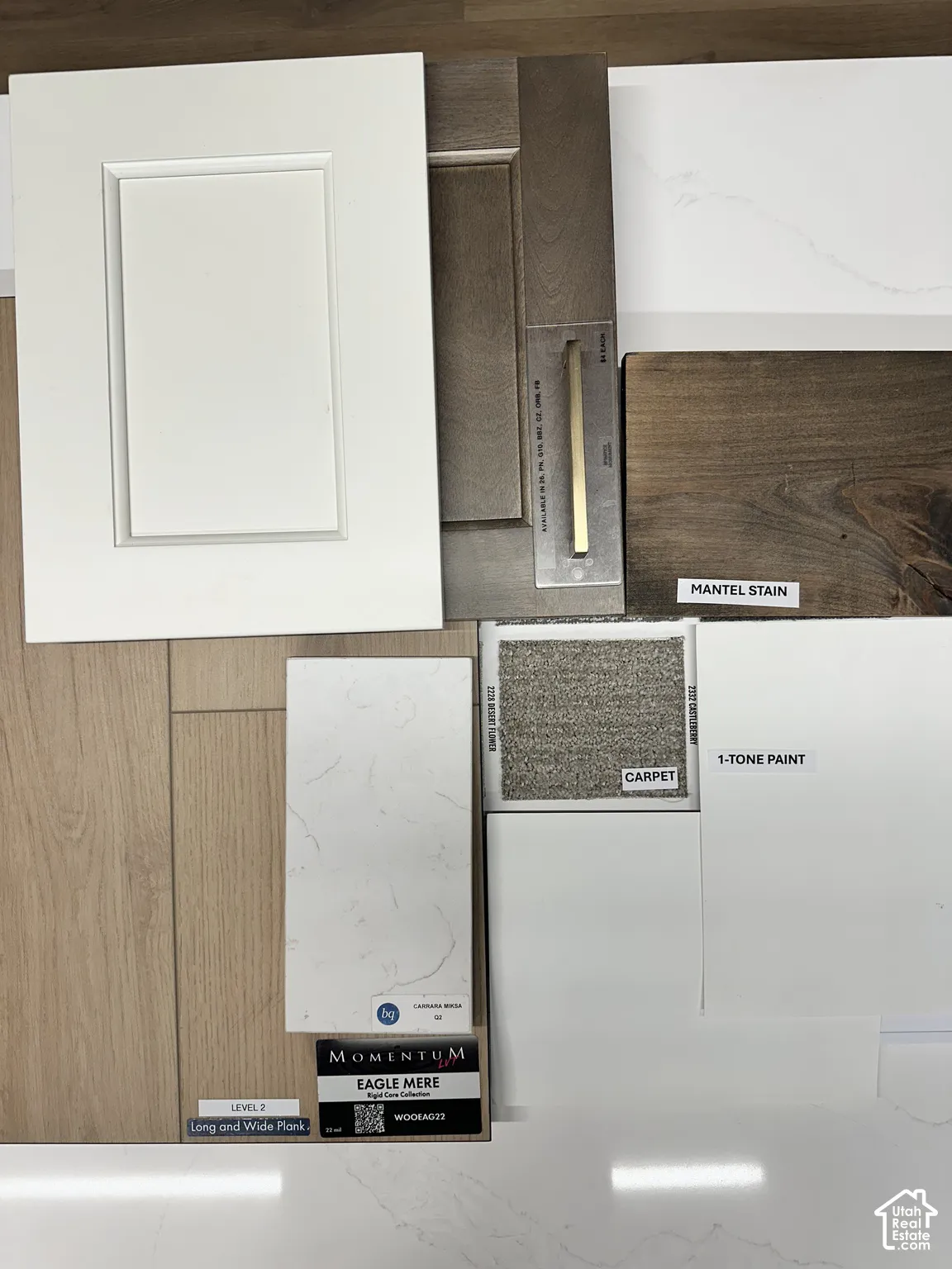 Custom selection of finishes including white shaker-style cabinetry, wood-finish wide plank flooring, veined stone-style countertops, neutral-toned carpeting, and dark-stained wood mantel finish